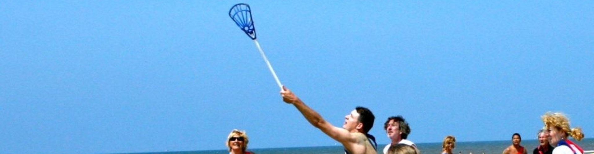 Beach lacrosse in actie tijdens een bedrijfsuitje op het strand.